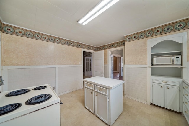 kitchen featuring tile walls, white cabinetry, a center island, and white appliances