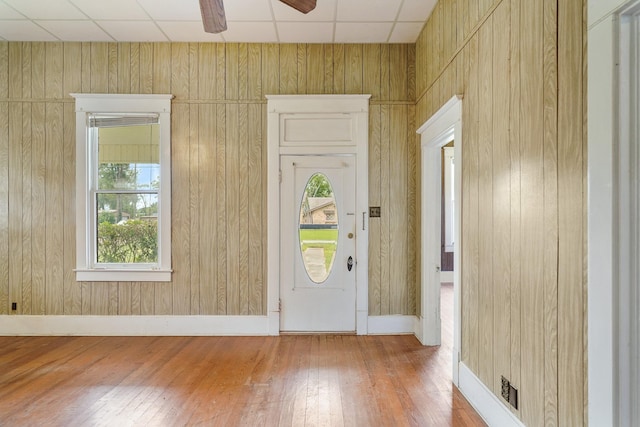 foyer with hardwood / wood-style floors, ceiling fan, and wooden walls