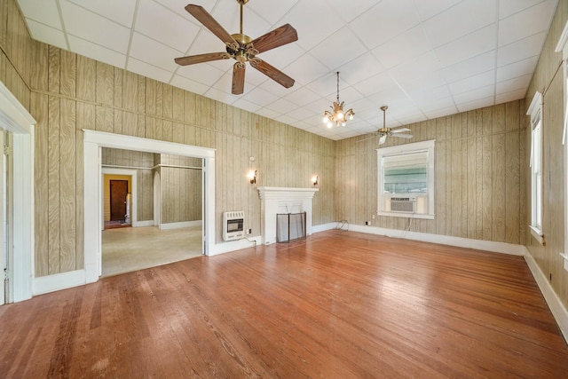 unfurnished living room with wood-type flooring, ceiling fan with notable chandelier, and heating unit