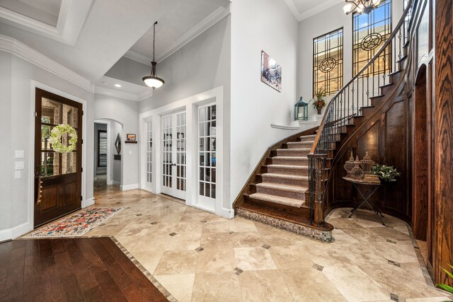 foyer with hardwood / wood-style floors, crown molding, and french doors