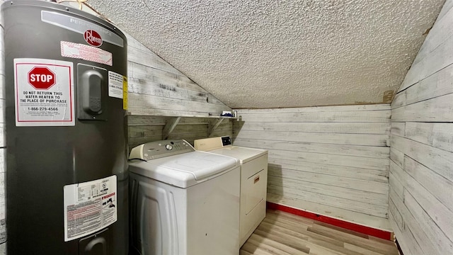 laundry room with electric water heater, light wood-type flooring, independent washer and dryer, and wooden walls