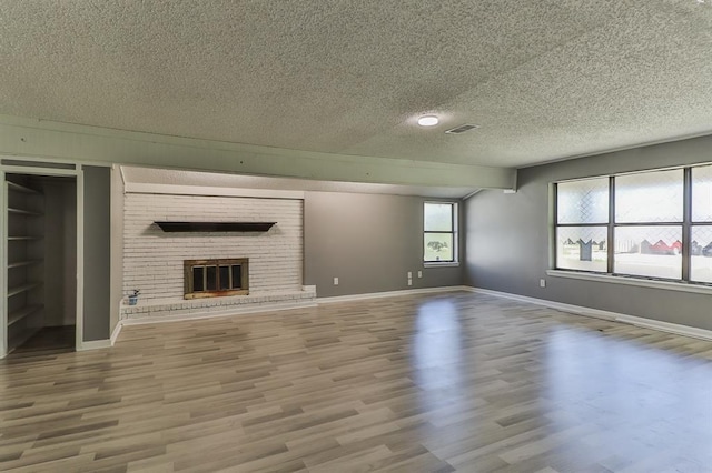 unfurnished living room with hardwood / wood-style flooring, a fireplace, and a textured ceiling