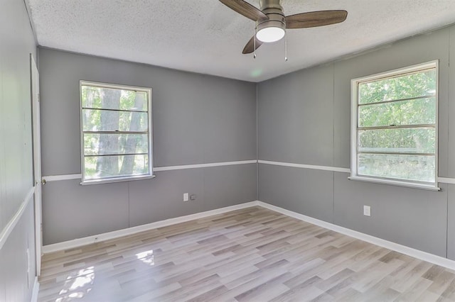 unfurnished room featuring plenty of natural light, a textured ceiling, and light hardwood / wood-style flooring