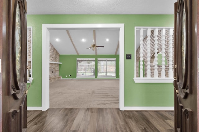 foyer entrance featuring brick wall, a textured ceiling, lofted ceiling, wood-type flooring, and ceiling fan