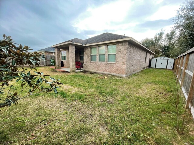 rear view of house featuring a yard and a storage shed