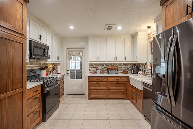 kitchen with tasteful backsplash, sink, black appliances, white cabinets, and light tile patterned flooring