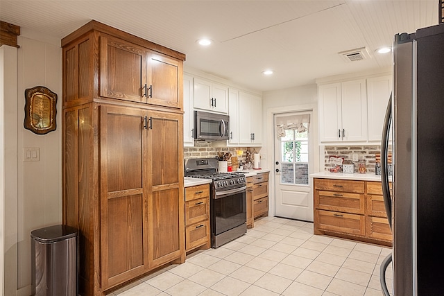 kitchen with gas stove, stainless steel refrigerator, backsplash, and white cabinets