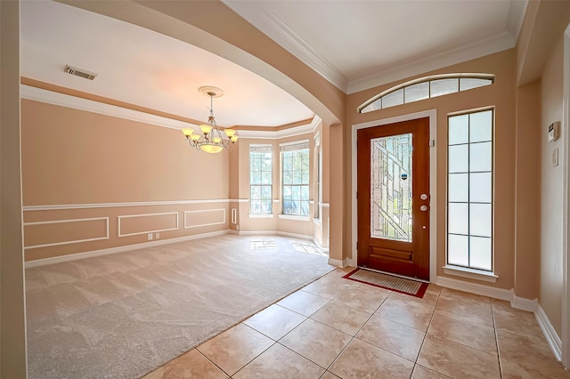 tiled foyer with crown molding and a chandelier