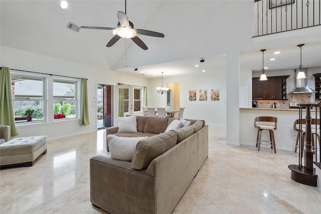 living room with vaulted ceiling, sink, and ceiling fan with notable chandelier