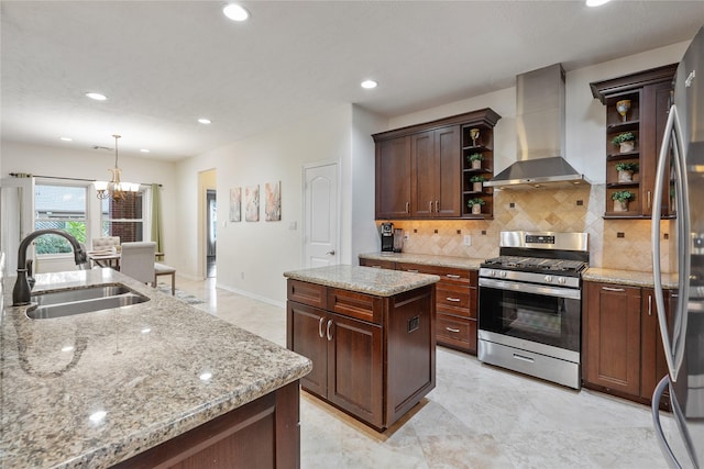 kitchen with wall chimney exhaust hood, stainless steel appliances, sink, decorative light fixtures, and a center island