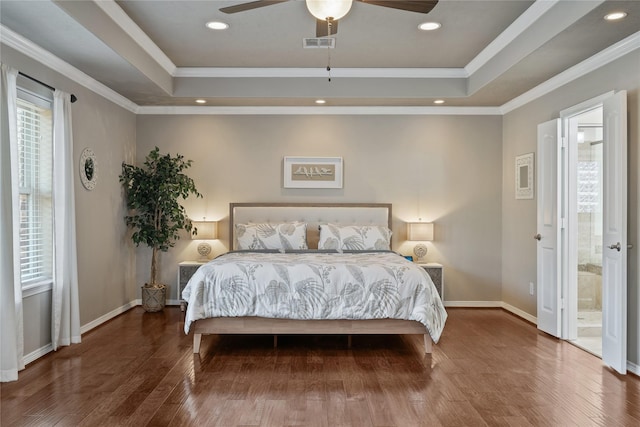 bedroom with ensuite bathroom, ceiling fan, multiple windows, and a tray ceiling