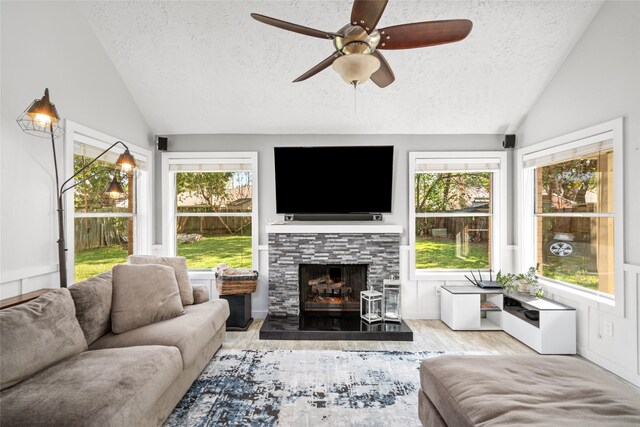 sunroom / solarium with a healthy amount of sunlight, vaulted ceiling, and a stone fireplace