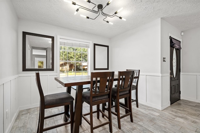 dining space featuring a chandelier, light hardwood / wood-style floors, and a textured ceiling