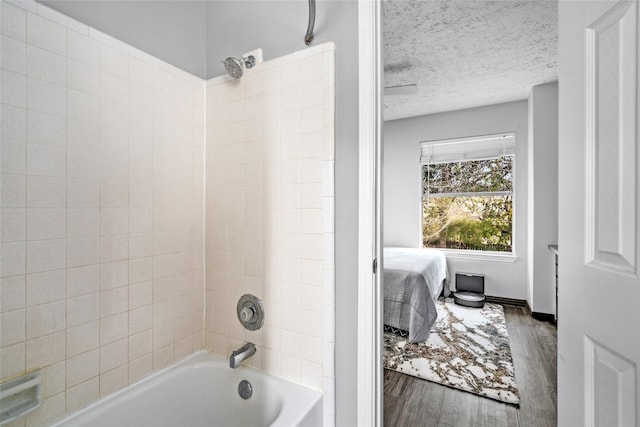 bathroom featuring a textured ceiling, tiled shower / bath, and hardwood / wood-style flooring