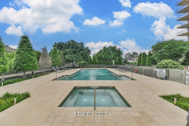 view of swimming pool featuring a hot tub and a patio