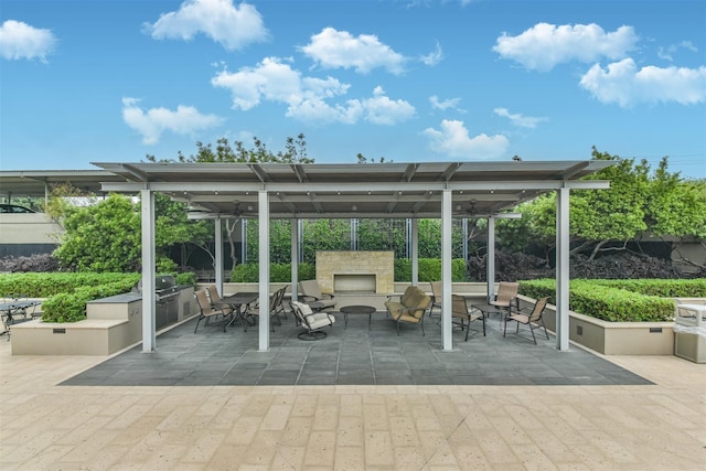 view of patio / terrace with exterior kitchen and an outdoor stone fireplace