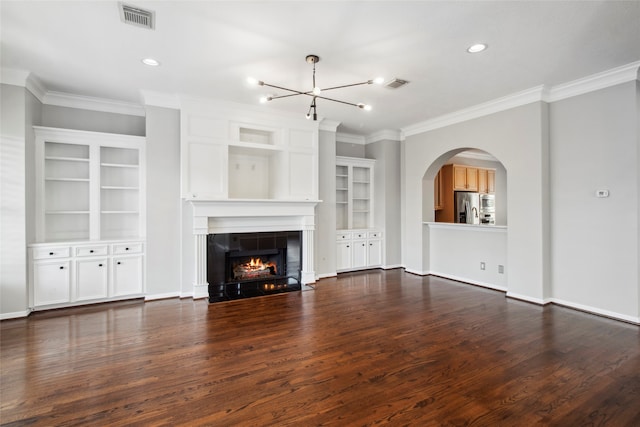 unfurnished living room with a fireplace, dark wood-type flooring, crown molding, and a notable chandelier