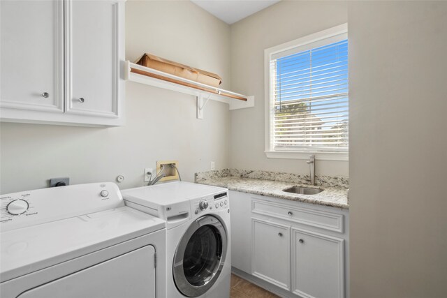 clothes washing area with cabinets, sink, and washer and dryer