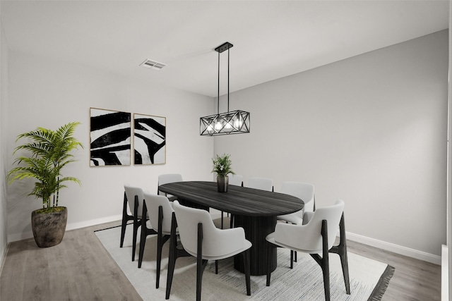 dining area with an inviting chandelier, wood finished floors, visible vents, and baseboards