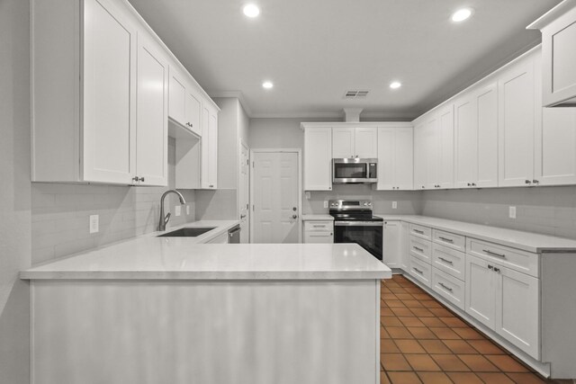 kitchen with kitchen peninsula, stainless steel appliances, tasteful backsplash, white cabinets, and sink