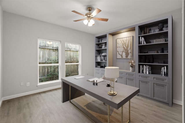 home office with ceiling fan, built in shelves, light wood-type flooring, and baseboards