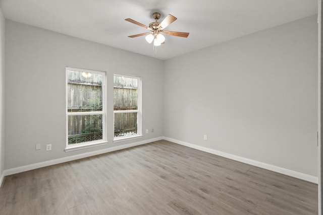 empty room featuring ceiling fan, wood finished floors, and baseboards