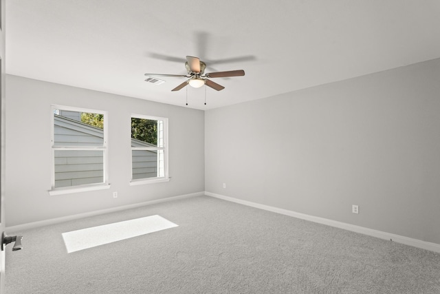 empty room featuring a ceiling fan, visible vents, light carpet, and baseboards