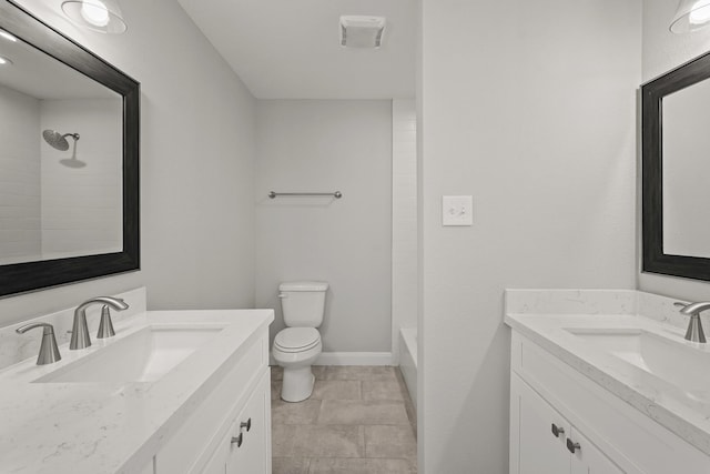 bathroom featuring two vanities, a sink, toilet, and baseboards