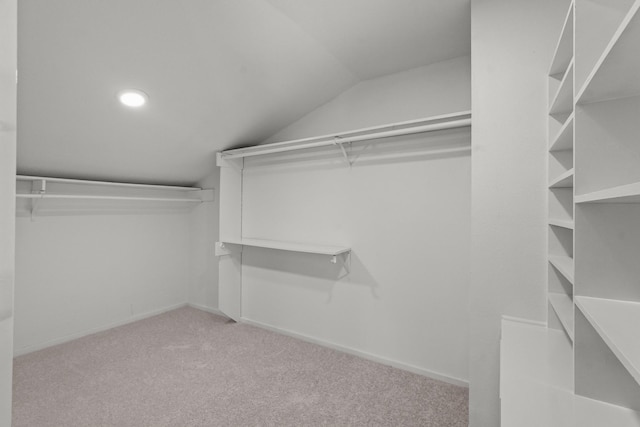 walk in closet with lofted ceiling and light colored carpet