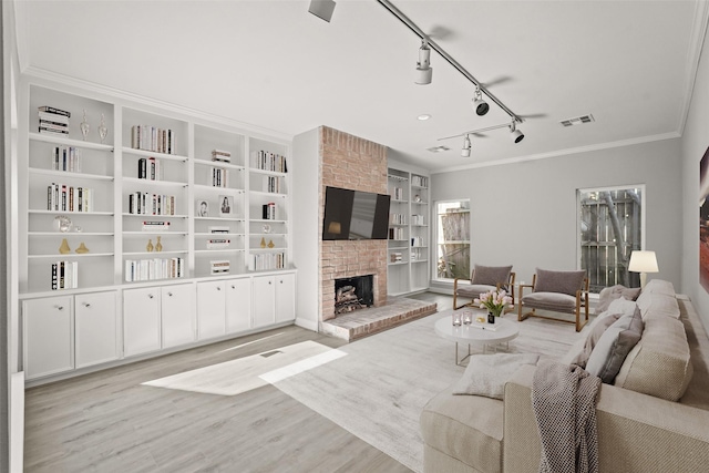 living area with built in shelves, a fireplace, visible vents, light wood-style flooring, and ornamental molding