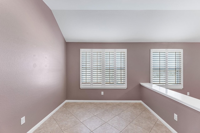 spare room featuring light tile patterned floors and vaulted ceiling