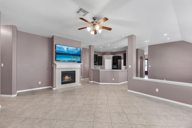 unfurnished living room featuring a tile fireplace, ceiling fan, and light tile patterned flooring