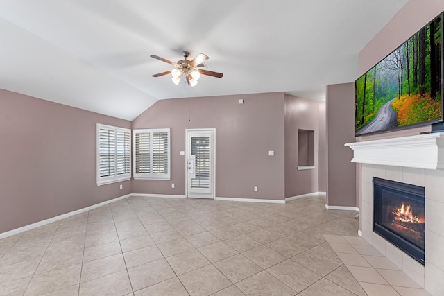 unfurnished living room featuring ceiling fan, a tiled fireplace, light tile patterned floors, and vaulted ceiling