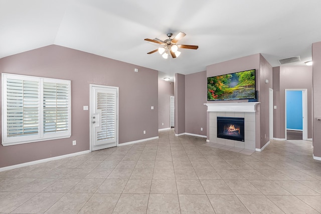 unfurnished living room with ceiling fan, light tile patterned floors, a tile fireplace, and vaulted ceiling