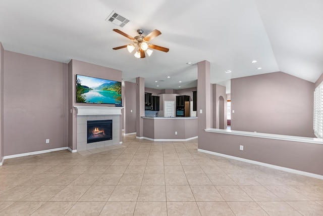 unfurnished living room with light tile patterned floors, vaulted ceiling, ceiling fan, and a tiled fireplace