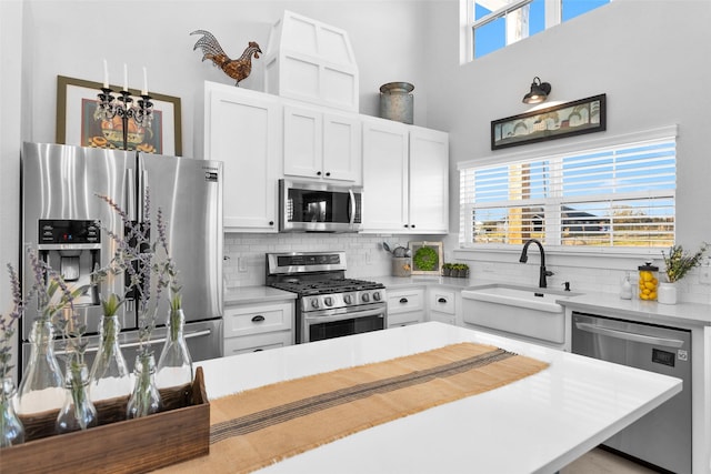 kitchen with stainless steel appliances, white cabinetry, a healthy amount of sunlight, and sink