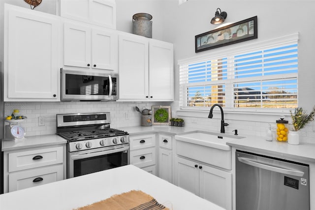 kitchen featuring white cabinets, backsplash, sink, and appliances with stainless steel finishes