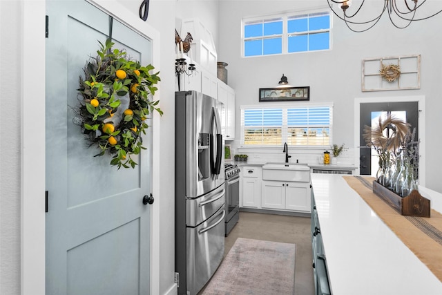 kitchen featuring white cabinetry, sink, hanging light fixtures, stainless steel appliances, and a chandelier