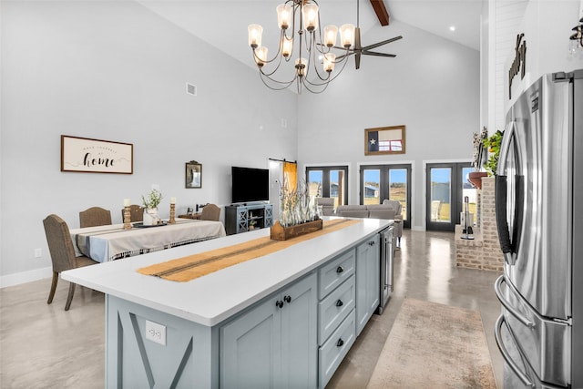 kitchen featuring french doors, beam ceiling, a center island, stainless steel refrigerator, and hanging light fixtures