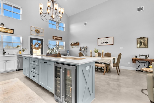 kitchen with a kitchen island, an inviting chandelier, white cabinets, wine cooler, and hanging light fixtures