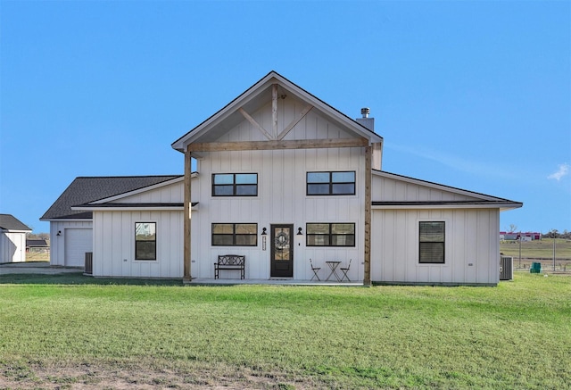 rear view of house with a garage, central AC unit, and a lawn