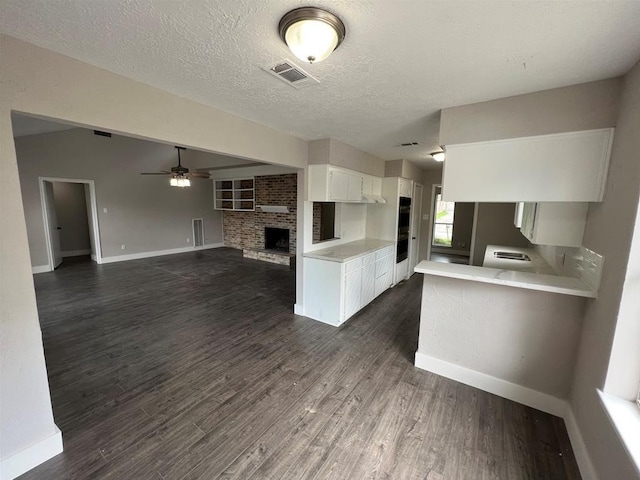 kitchen featuring kitchen peninsula, a textured ceiling, ceiling fan, dark hardwood / wood-style floors, and white cabinetry