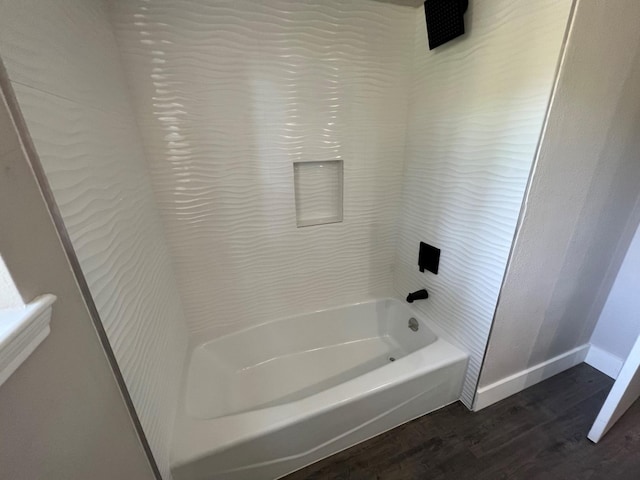 bathroom with washtub / shower combination and wood-type flooring