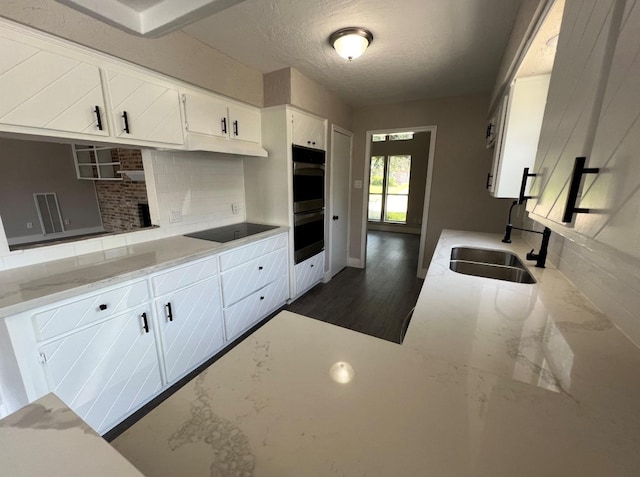 kitchen with white cabinets, a textured ceiling, black electric cooktop, and sink