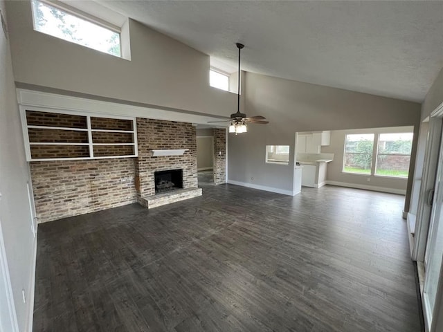 unfurnished living room featuring ceiling fan, dark hardwood / wood-style floors, high vaulted ceiling, and a brick fireplace