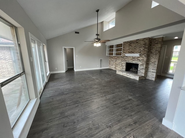 unfurnished living room with plenty of natural light, ceiling fan, dark wood-type flooring, and a brick fireplace