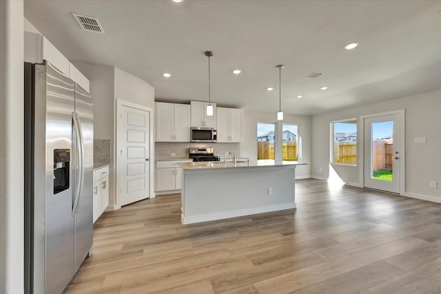 kitchen with white cabinetry, stainless steel appliances, decorative light fixtures, decorative backsplash, and a center island with sink