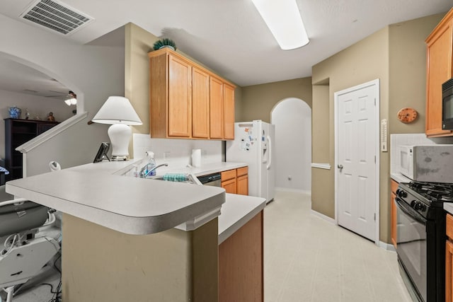 kitchen with a breakfast bar, black appliances, sink, ceiling fan, and kitchen peninsula