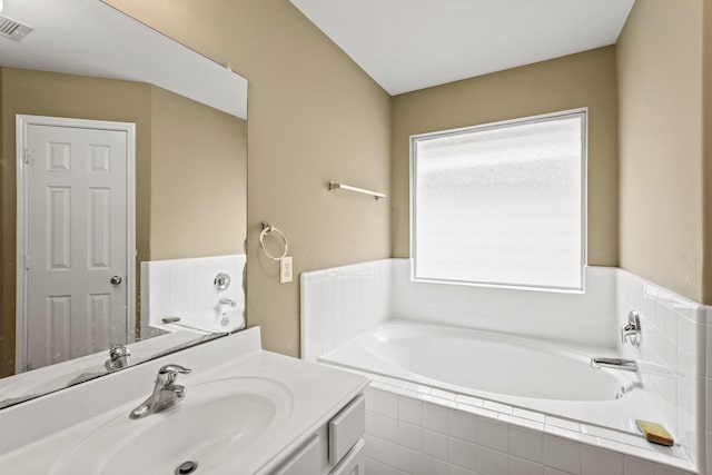 bathroom featuring vanity, plenty of natural light, and tiled tub