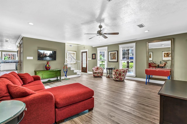 living room with hardwood / wood-style flooring, a textured ceiling, ceiling fan, and ornamental molding